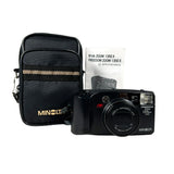 Minolta camera with black carrying case and instruction manual on a white background