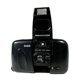 A vintage black Kodak Focus Free 35mm camera with the flash extended open, photographed against a neutral light gray background.