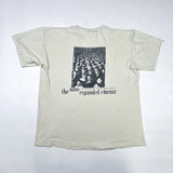A vintage off-white graphic t-shirt laid flat on a white background. The shirt features a black-and-white photograph of a crowded movie theater audience with the text 'the niaro expanded cinema' printed below.