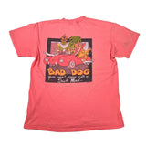 A coral pink short-sleeve t-shirt laid flat on a white background, featuring a large graphic print on the front with a cartoon red car, a dog, and the text 'BAD DOG you can't argue with a Sick Mind.