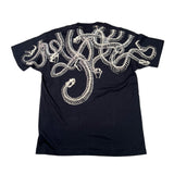 A black short-sleeve t-shirt laid flat on a white surface, featuring a large graphic print of intertwined snake skeletons across the back in a light beige color.