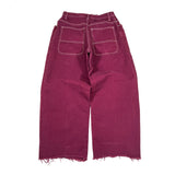 Maroon jeans with frayed hems on a white background