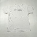 A white short-sleeve t-shirt laid flat on a light gray surface, featuring a small black graphic on the upper back that reads 'R.E.