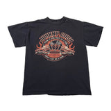 A black short-sleeve graphic T-shirt laid flat on a white fabric background. The front features a large circular chest graphic with a skull, crossed pistols, flames, and stylized text reading 'Johnny Cash' and 'You Cost Me More Than Life.