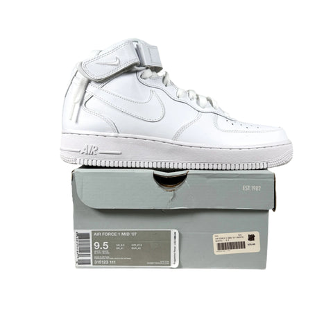 White Nike Air Force mid-top sneaker on top of a gray shoe box with visible branding.