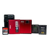 Collection of camera accessories including a red camera, battery, charger, and memory card on a white background.