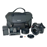 Nikon camera bag with camera, lens, battery, and accessories on a white background