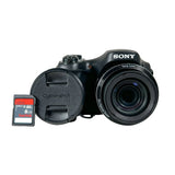 A black Sony digital camera with its lens cap off, shown next to an 8GB SanDisk Ultra microSD SD card on a light gray background.