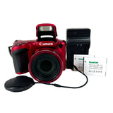 Red Canon camera with battery and charger on a white background