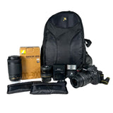 Camera equipment including a backpack, camera, lenses, and accessories on a white background