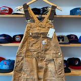 Brown overalls on a hanger with hats displayed on shelves in the background