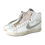 A pair of white Nike high-top sneakers with a light pink lining and a gray Swoosh, photographed on a light gray background.