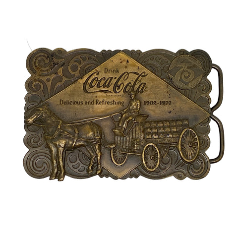 Bronze Coca-Cola belt buckle with horse and carriage design on a white background