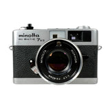 A vintage Minolta Hi-Matic 7SII SLR camera with a silver top and bottom and a black textured grip, shown against a plain white background.