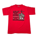 A red short-sleeve graphic t-shirt laid flat on a white background. The front features a distressed black, white, and red graphic print with the text 'SAN DIEGO ARTS FESTIVAL' and 'TREASURES OF THE SUVET UNION' alongside a stylized illustration of St.