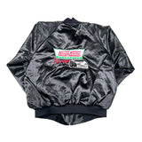 A black satin bomber jacket laid flat on a white background, featuring a large back graphic with the Krispy Kreme logo and the word 'Racing' alongside a white race car.