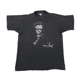 A faded black graphic t-shirt featuring a white portrait print of Fidel Castro and his signature, laid flat on a white fabric background.