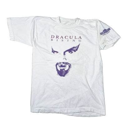 A white vintage graphic t-shirt featuring a purple stylized face print and the text 'DRACULA RISING' on the front, laid flat on a light background.