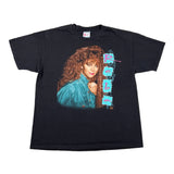 A black short-sleeve graphic T-shirt laid flat on a white background, featuring a large printed portrait of a woman with curly brown hair and a turquoise outfit, alongside vertical stylized text.