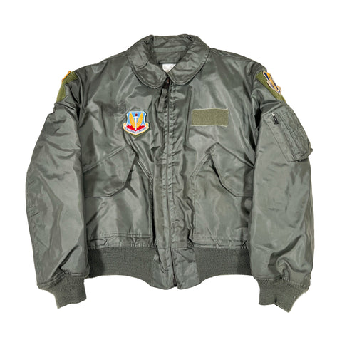 Green military-style jacket with patches on a white background