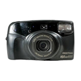 A black Pentax IQ Zoom 200 compact camera photographed from the front on a light gray to white studio background.