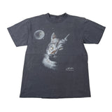 A faded dark gray short-sleeve t-shirt featuring a graphic print of a wolf's head next to a full moon under a starry sky. The shirt is laid flat on a light gray background.