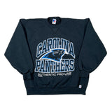 A black Carolina Panthers crewneck sweatshirt laid flat on a white background, featuring a large blue and white graphic with the team logo and 'AUTHENTIC PRO LINE' text.