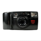 A vintage black Kodak Star Zoom 105 compact camera with red branding text, shown from the front on a light gray textured background.