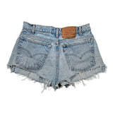 Light wash blue denim shorts with a raw frayed hem, featuring the iconic back pockets and a brown leather patch on the waistband.