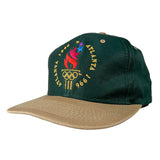 A dark green baseball cap with a tan visor, featuring a colorful embroidered Atlanta 1996 Olympic theme on the front panel.