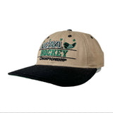 A khaki and black baseball cap featuring embroidered 'NCAA Hockey Championship' text and a green hockey graphic on the front panel, photographed on a light gray background.