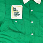 Green shirt with a label on the chest pocket displaying text.