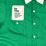Green shirt with a label on the chest pocket displaying text.