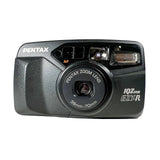 A vintage Pentax IQZ EZYR compact camera in black, photographed from the front on a light gray textured background.