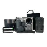 Sony 10x Megapixel digital camera in silver and black, shown with its battery, charger, and printer cartridge on a white background.