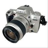 A Minolta Stadi MAXXUM SLR mirrorless camera with a silver body and black lens, photographed on a plain white background.