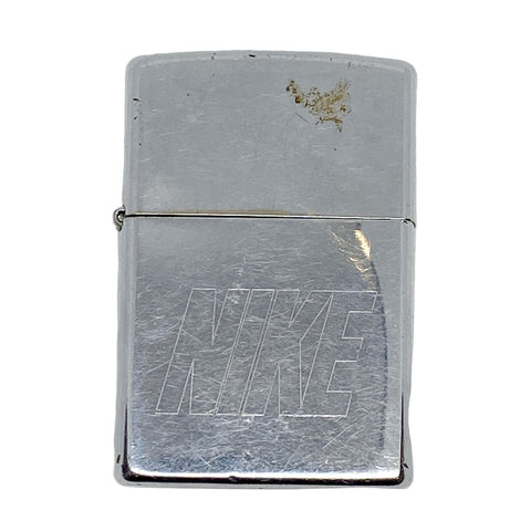 Silver Zippo lighter with 'Nike' logo on a white textured background