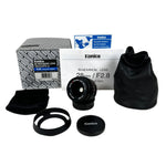 Konica camera lens with accessories and packaging on a white background