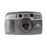 A vintage silver Pentax IQZcom EZY-80 compact camera with a gray body and silver accents, photographed against a clean white background.