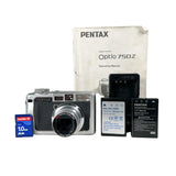 A Pentax Optio 750Z digital camera in silver and black, displayed with its manual, batteries, a Pentax SD card, and a battery charger on a light gray background.