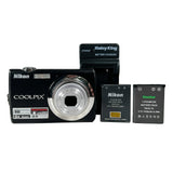 Nikon Coolpix camera with battery and charger on a white background