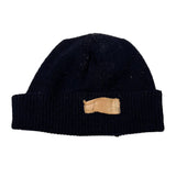 Black knitted dog muzzle with a tan leather strap on a white background