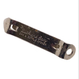 A vintage metal can and bottle opener engraved with the brand name 'Quick and Baby', shown on a textured white background.