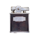 A vintage metal lighter with a dark brown enamel body and silver-toned metal top, photographed on a textured white background.