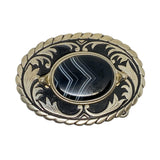 Decorative brooch with black stone and gold-like metalwork on a white background