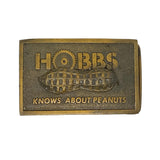Bronze belt buckle with 'Hobbs Knows About Peanuts' text and peanut design on a white background