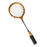 A vintage wooden tennis racket with black wrapped grip and white strings, displayed diagonally on a textured white wall.