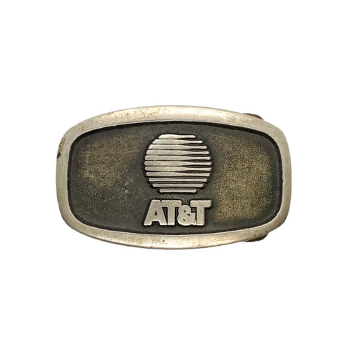 Vintage AT&T logo on a metal belt buckle against a white background
