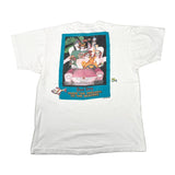 A white short-sleeve t-shirt laid flat on a light gray background, showing the back side with a large colorful graphic print. The graphic features cartoon characters in a pink car with a turquoise border and text reading '24 hrs.