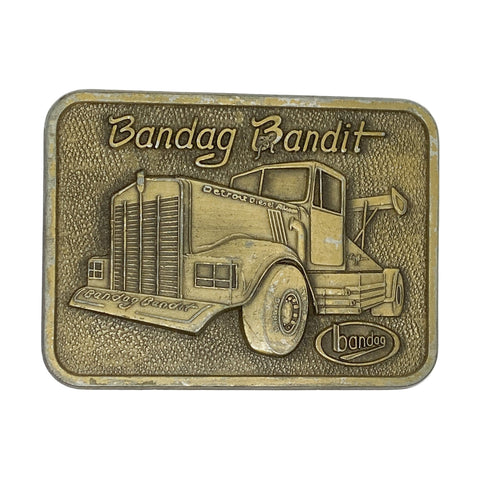 Bronze belt buckle with truck design and 'Bandag Bandit' text on a white background